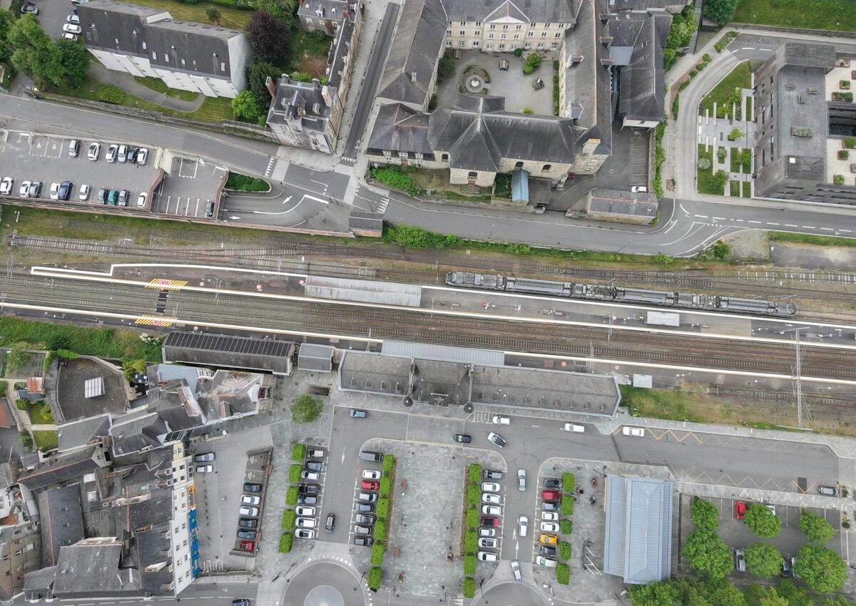La gare de Vitré photographiée par drone en 2026, sous le même angle, avec deux voies principales, un parking et une passerelle moderne